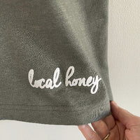 Local Honey in script font, white flock on back of tshirt bottom right hem