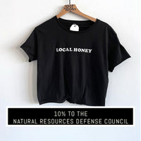 Black cropped tshirt with raw hem and raw edge sleeves. White flocked lettering "LOCAL HONEY"